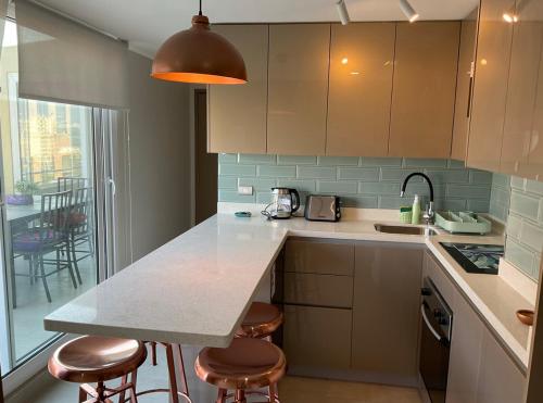 a kitchen with a counter and stools in it at Apartament Condo Amueblado, ENCOMENDEROS 200 El Golf, Las Condes Santiago con vista al Costanera Center in Santiago