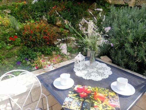 a table with plates and a vase of flowers on it at Rooms Villa Gala in Mlini
