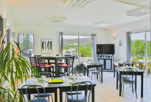 a restaurant with tables and chairs and a tv at Sev'hotel in Sévérac-le-Château
