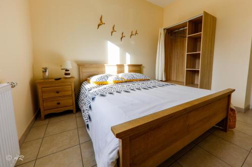 Thiergevilleにあるla grange aux hortensiasのベッドルーム1室(白いシーツを使用した大きな木製ベッド1台付)