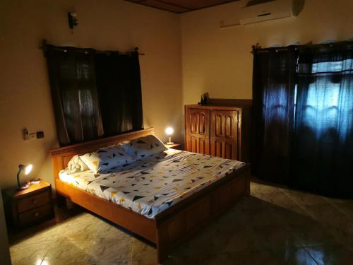 a bedroom with a bed and two windows with curtains at ROMO house in Cotonou