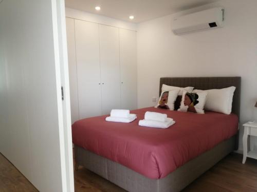 a bedroom with a red bed with two dolls on it at CAIS DE APRESENTAÇÃO NO CORAÇÃO DE AVEIRO in Aveiro