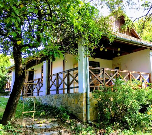 una casa con un árbol delante de ella en Lóci Palócház, en Nagylóc