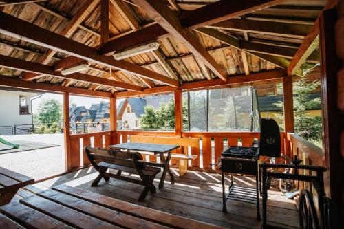 eine Holzterrasse mit einem Tisch und einer Bank in der Unterkunft New Willa Jan in Zakopane