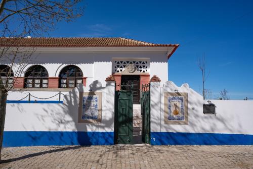 a white and blue house with a green door at Escola do Fado in Vila Fernando