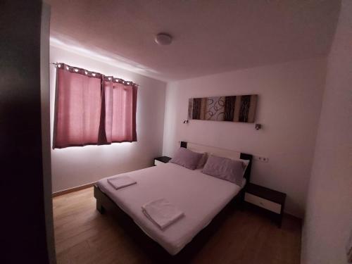 a bedroom with a bed with white sheets and a window at Frane Apartment in Zavalatica