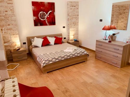 a bedroom with a bed with red pillows and a dresser at Perla Barocca Centro Storico Mesagne in Mesagne