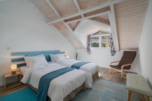 a bedroom with two beds and a chair and a window at The Rum Inn in Calheta