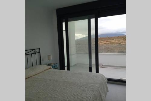 Un dormitorio con una cama y una ventana grande. en Atico Casa Kyara, con gran Terraza y Parking, Iceberg Albacerrado, en Tarifa