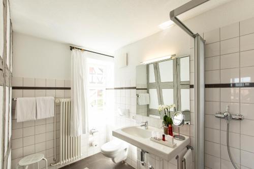 a white bathroom with a sink and a toilet at Hotel de Charme Römerhof in Arbon