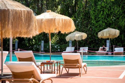 a group of chairs and umbrellas next to a pool at Montespina Park Hotel in Naples