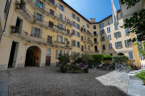 a large yellow building with a courtyard at Harmony Navigli Apartment in Milan