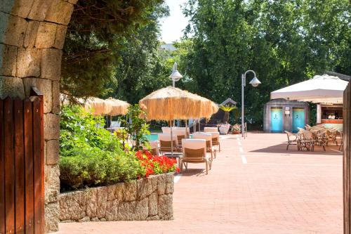 a patio with tables and chairs and umbrellas at Montespina Park Hotel in Naples