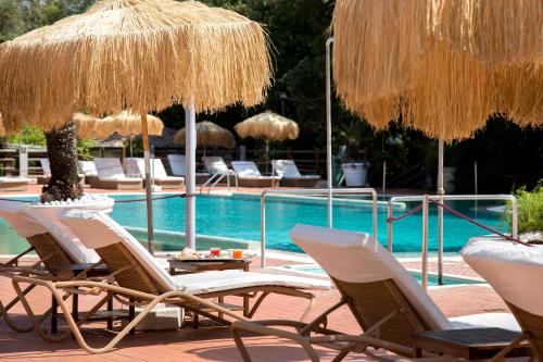 a group of chairs and umbrellas next to a swimming pool at Montespina Park Hotel in Naples