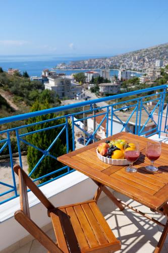 a table with a bowl of fruit and two glasses of wine at Miracle Apartments Saranda in Sarandë