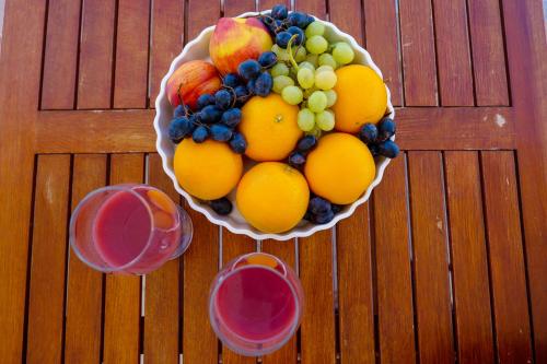 a bowl of fruit on a table with two glasses at Miracle Apartments Saranda in Sarandë