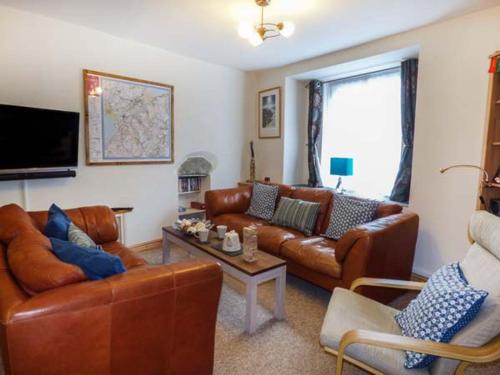 a living room with leather couches and a tv at Meirionfa base for Snowdon in Llanberis