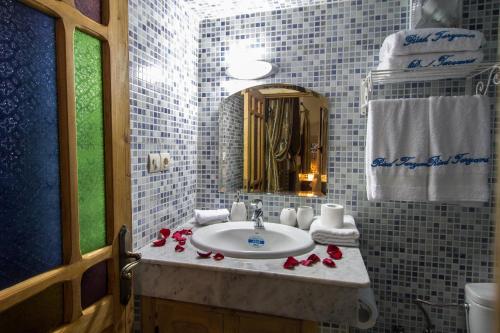 un baño con lavabo con rosas rojas. en Riad Taryana, en Fez