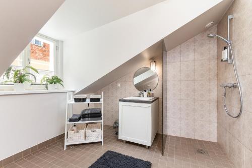 a bathroom with a shower with a mirror and a sink at Lossi Old Town Apartment in Tartu
