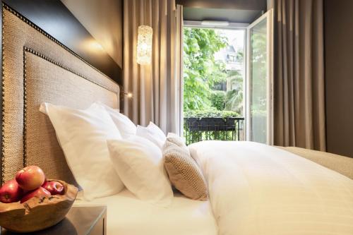 a bed with white pillows and a bowl of fruit on a table at B Montmartre in Paris