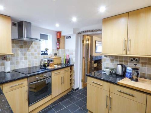 a kitchen with wooden cabinets and black counter tops at Meirionfa base for Snowdon in Llanberis