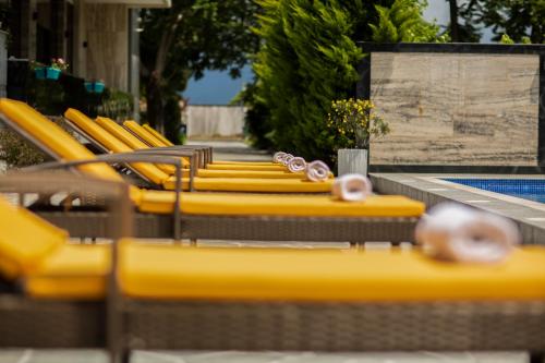 a row of yellow chairs next to a swimming pool at Chveni Ezo Boutique Hotel in K'obulet'i