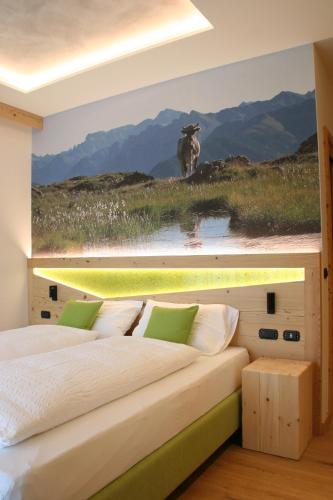 a bedroom with a bed with a painting of a cow at Agriturismo Maso Schneider in Cavalese