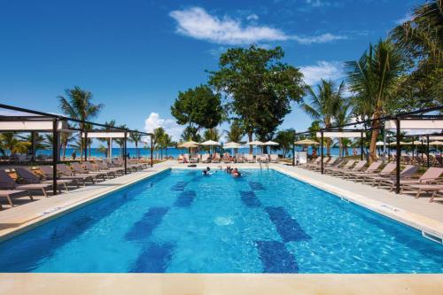 a swimming pool with chairs and the ocean in the background at Riu Palace Tropical Bay - All Inclusive in Negril