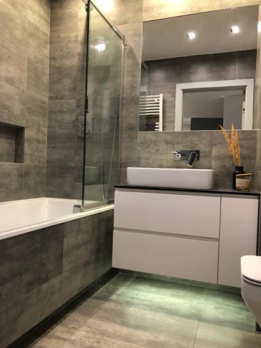een badkamer met een wastafel, een bad en een toilet bij Apartament Avior in Iława