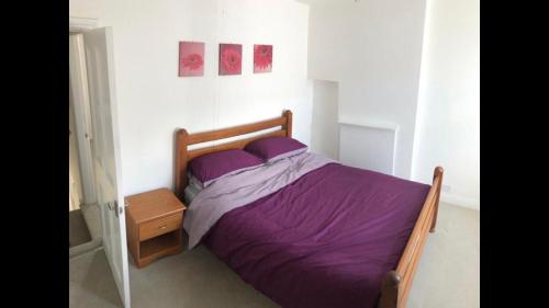 a bedroom with a bed with purple sheets and a nightstand at Cosy end terrace in Lancaster