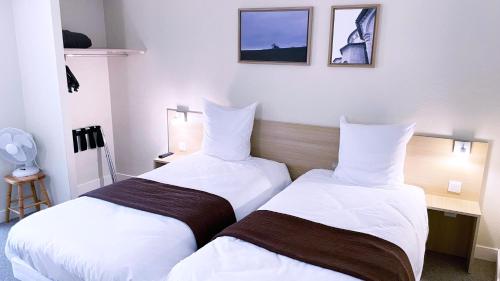 two beds sitting next to each other in a hotel room at Abelha Hôtel Le France in Brive-la-Gaillarde