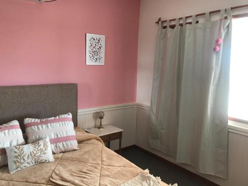 a bedroom with pink walls and a bed and a window at LOS TEROS POSADA DE CAMPO in San Rafael