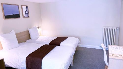 a room with two beds in a hotel room at Abelha Hôtel Le France in Brive-la-Gaillarde