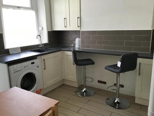 a kitchen with a washing machine and two bar stools at Cosy end terrace in Lancaster