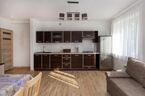 een keuken met bruine kasten en een bank in een kamer bij przystanek Kudowa in Kudowa-Zdrój