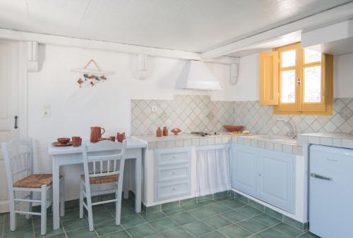 a kitchen with white cabinets and a table and chairs at Kalderimi Residencies in Astypalaia Town