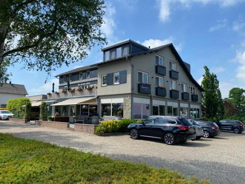 a large building with cars parked in front of it at Hotel de Plank - alle kamers met airconditioning in Noorbeek