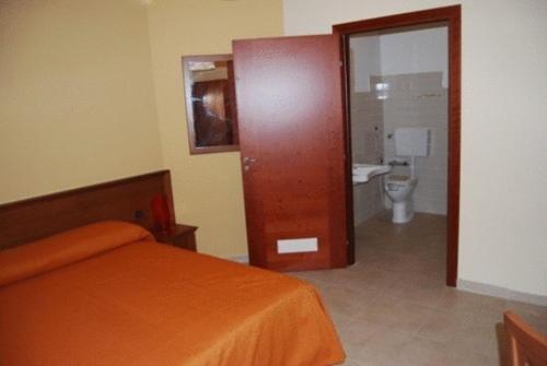a bedroom with a bed and a bathroom with a toilet at Hotel Poma in Custonaci