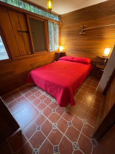 a bedroom with a red bed in a wooden room at Caoni Riverside Suites - Birders Paradise by the river, Ecuadorian Chocó in Puerto Quito