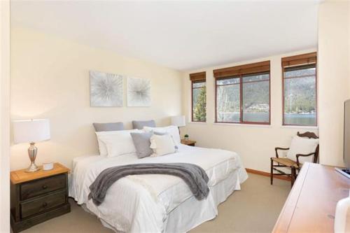 a white bedroom with a large bed and windows at Beautiful 2 bedroom overlooking Whistler's Green Lake and Mountains! in Whistler