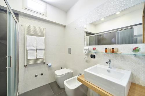 a white bathroom with a sink and a toilet at Sweet Central Hotel in Caserta