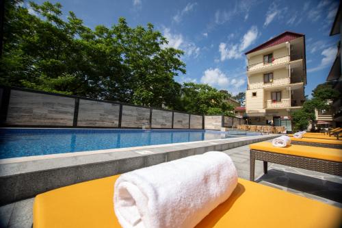 una mesa amarilla con una toalla junto a la piscina en Hotel Chveni Ezo, en Kobuleti