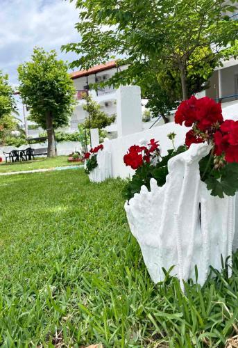 a white grave with red flowers in the grass at Antonia Rooms in Skála Foúrkas