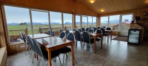 a dining room with tables and chairs and windows at Guesthouse Nypugardar in Höfn