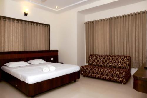a bedroom with a bed and a chair at Hotel Sai Ramanand in Shirdi