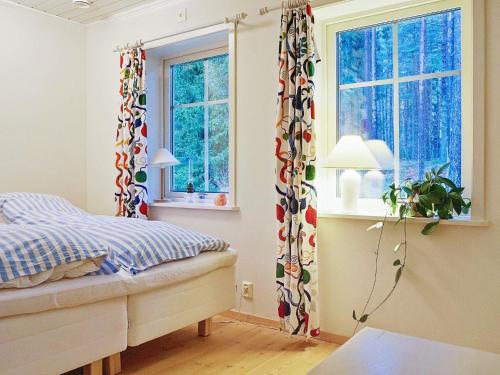 ein Schlafzimmer mit einem Bett und zwei Fenstern in der Unterkunft Holiday home VäTö in Harg