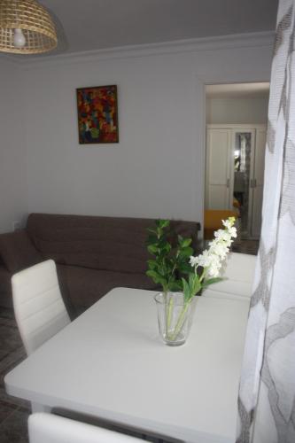 a white table with a vase of flowers on it at La Moradita in Vejer de la Frontera
