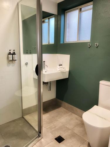 a bathroom with a shower and a sink and a toilet at Bay House Motel in Bateau Bay