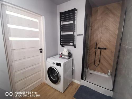 a washing machine in a bathroom with a shower at Komfortowe pokoje w Gdańsku w pobliżu jeziora i lasu in Gdańsk