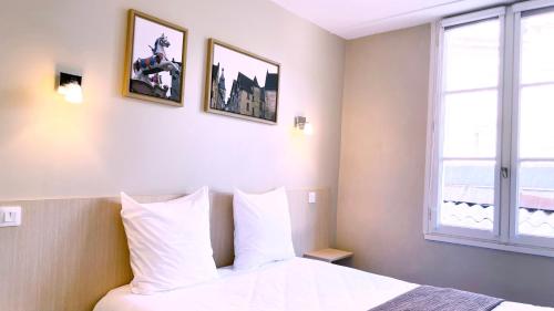 a bedroom with a bed with white pillows and a window at Abelha Hôtel Le France in Brive-la-Gaillarde